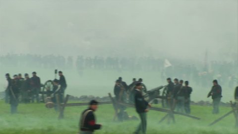 GETTYSBURG, PENNSYLVANIA - JULY 2008 - large-scale, epic Civil War anniversary reenactment -- in the middle of battle.  Wide of Union and Confederate soldiers firing and fighting, cannons and smoke.