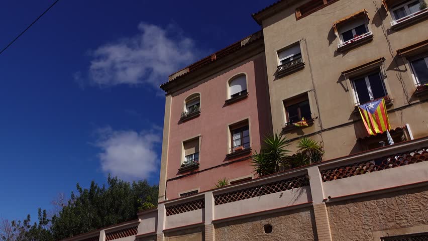 Modern Barcelona house facade, low angle panning shot. Estelada flag hang down from windows. Sunny day time, typical low rise residential building at La Salut area, Gracia district