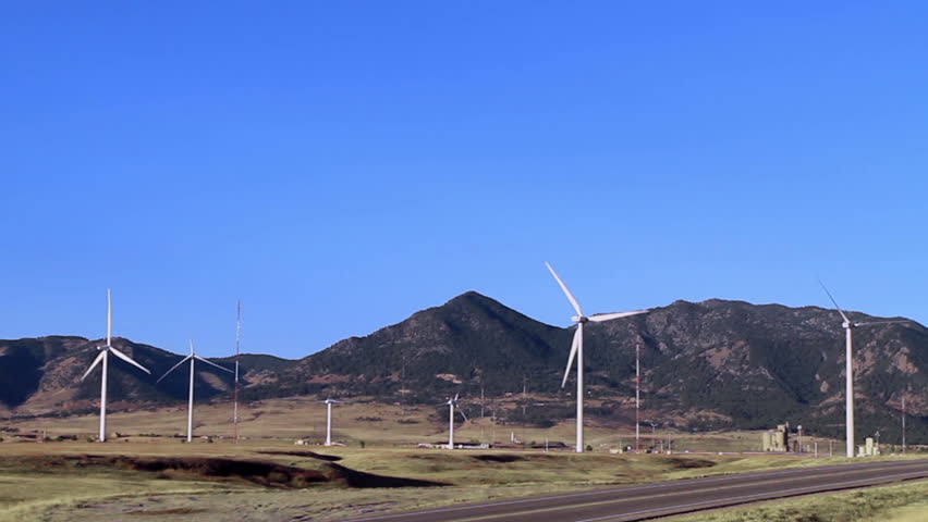 Huge wind turbines, with a backdrop of the Rocky Mountains. HD 1080p