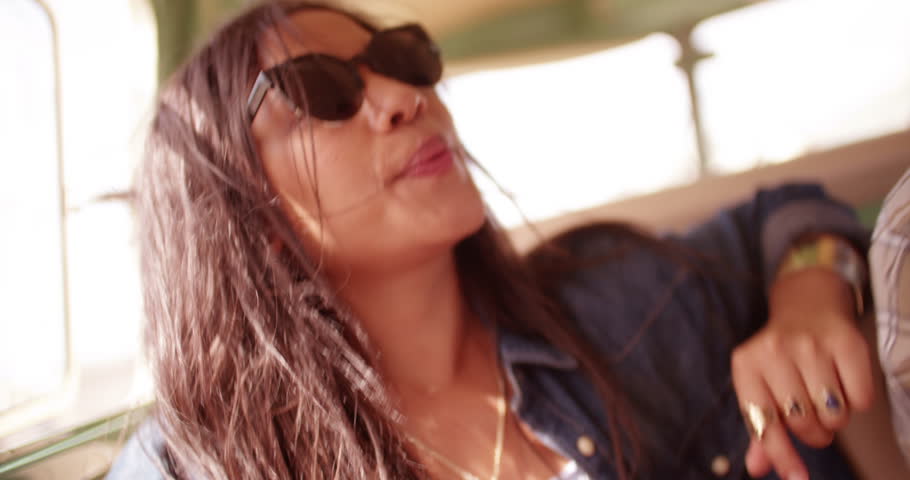 Happy Hipster Mixed Raced woman singing while traveling in retro van during road trip.