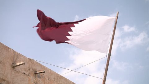 Qatari flag waves in the Souq Waqif standing market in Doha, Qatar
