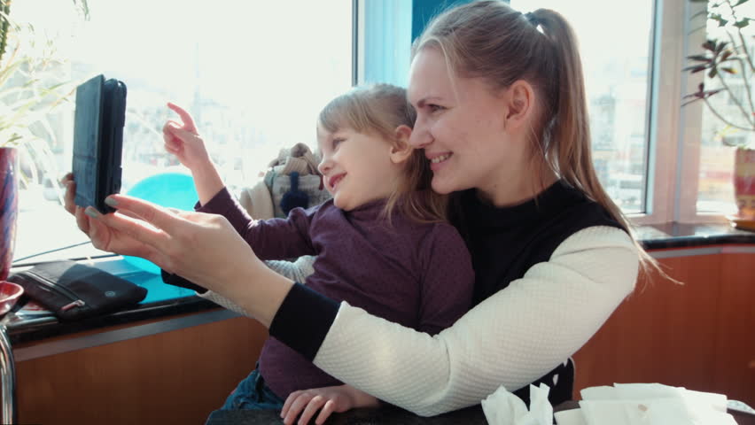 Mother and daughter are doing selfie in the restaurant of fast food