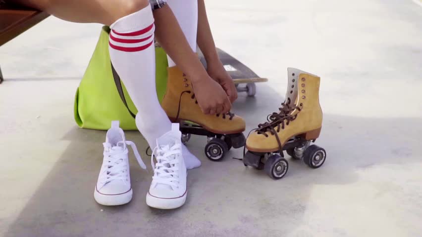 Young woman sits on bench to tie her skates