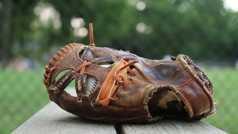 A basesball glove is picked up off a little league bench in a park / New York, New York - USA., June, 2014