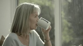 Beautyful retired senior woman with cup of tea looking at of window - Powered by Shutterstock - Get 15% off with code: PIKWIZARD15
