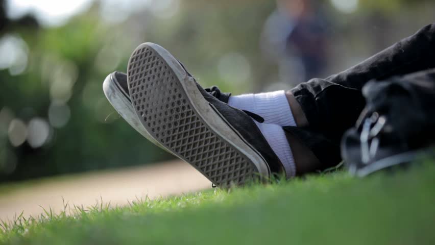 Relaxing day. Person laid down in the grass with feet crossed casually