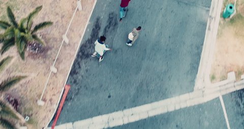 Aerial View of african American friends in shorts and hoodie skating on his skateboard on an parking lot