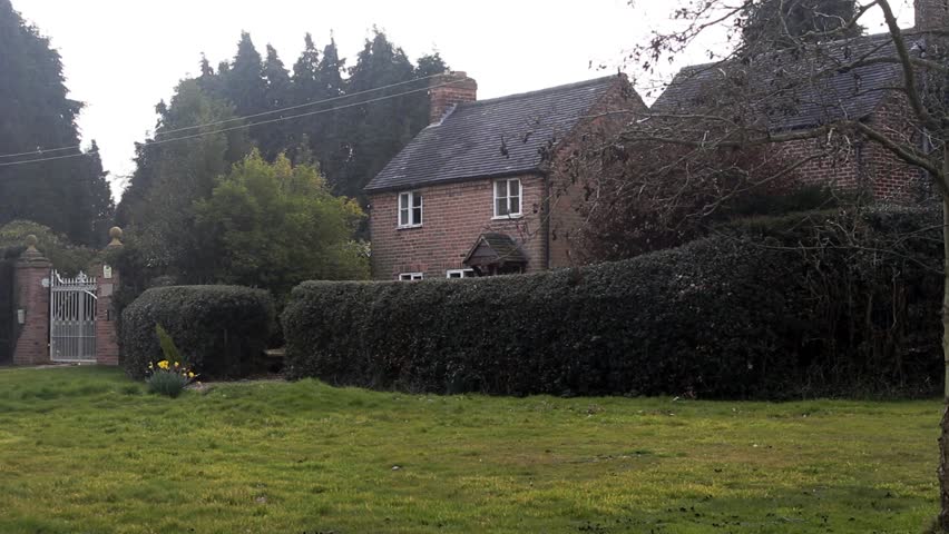 A cottage half hidden by trees on the edge of a forest