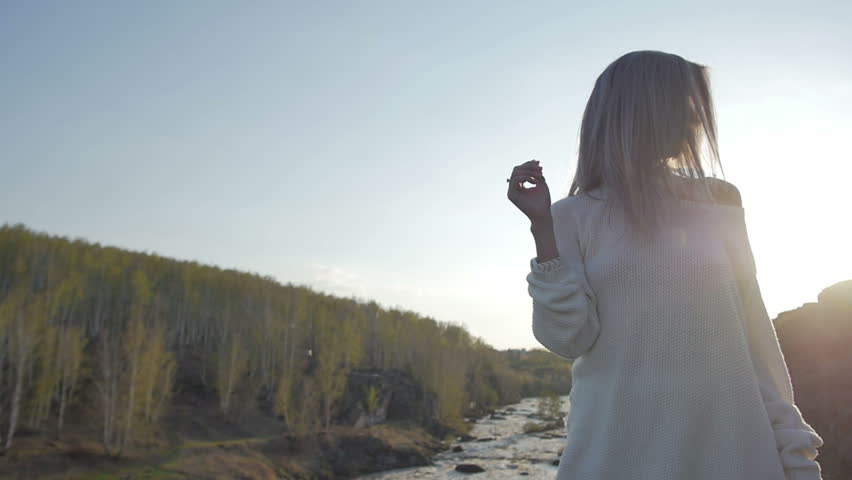 Girl stands on a rock on a background of the river