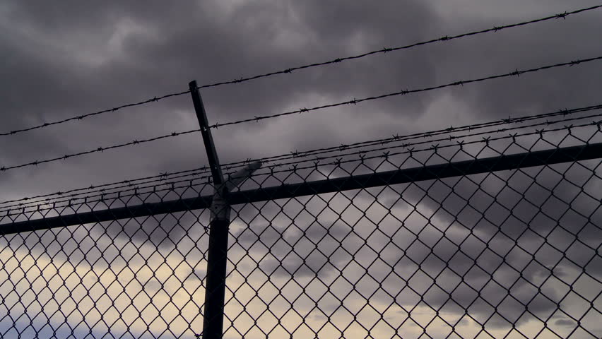 Barbwire fence with dark clouds time lapse