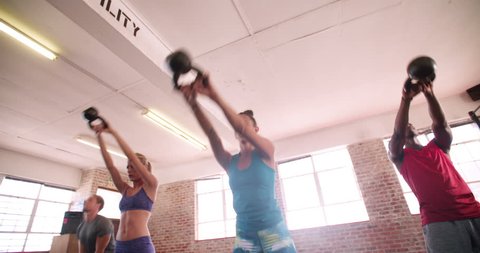 Multi-ethnic group of young adult athletes doing kettlebell exercise during a crossfit workout at the gym