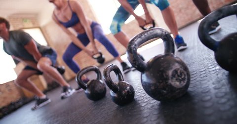 focus on Kettlebells on crossfit training. group of young adult athletes doing kettlebell exercise during a crossfit workout at the gym