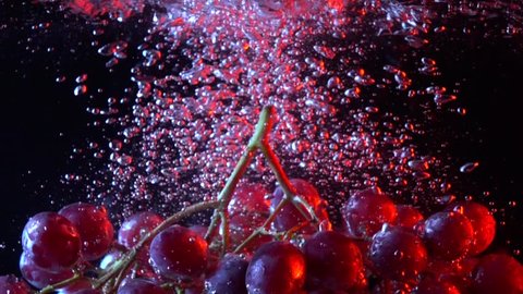 Bunch of red grapes falling into water close up super slow motion shot