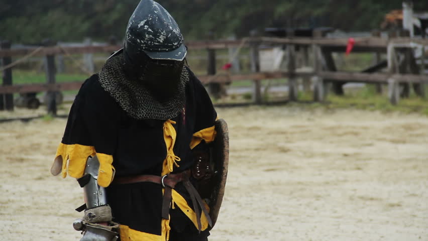 Brave knight with sword and shield in hands breathing heavily after fierce clash