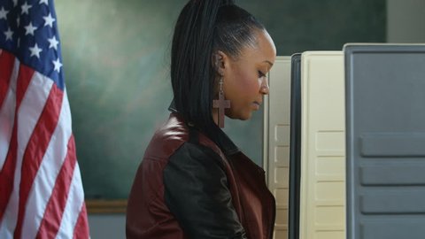 Black female voting in a voting booth, profile shot