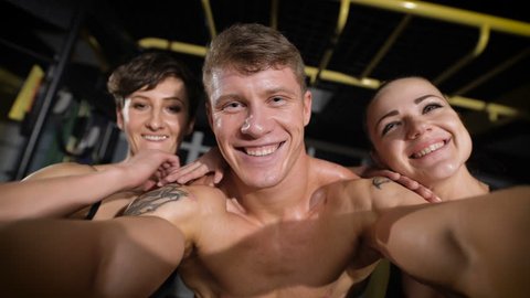 Two girl and one man making selfie photo in gym 