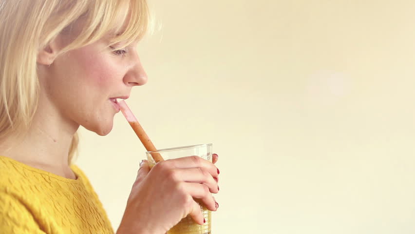 Close-up of profile face of a young woman drinking smoothie, in slow motion, graded