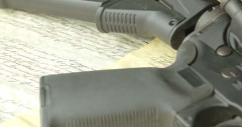 4K panning shot of a gun lying on top of the Constitution. Ammunition is also seen on the document.