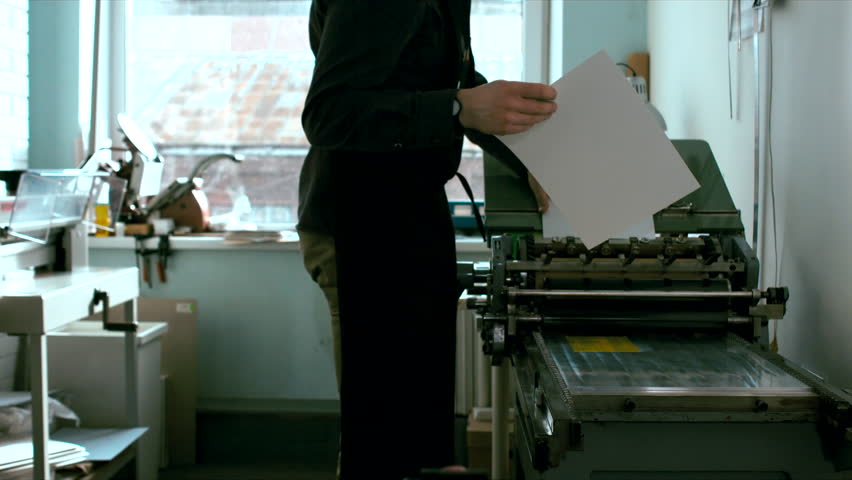 Caucasian male preparing a vintage letterpress machine for printing. Dolly in tracking 4k 60 FPS. Shot with Blackmagic URSA Mini