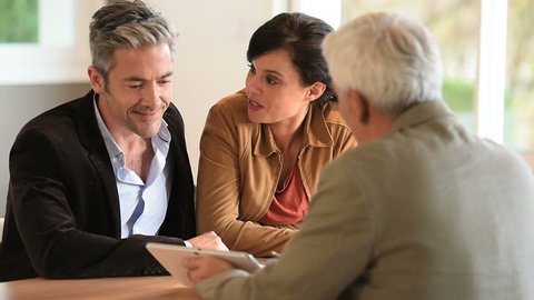 Mature couple signing documents in real-estate agency