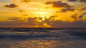 Beautiful sunrise cloudscape over ocean background. Sun rays beaming through picturesque clouds above sea, moderate surfing. Nature stunning sunrise in the ocean video