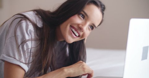 woman on bed is using her laptop to browse the web. Just wearing underwear and her beautiful smile.