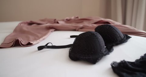 Black sexy underwear decorated on bed next to her bathrobe