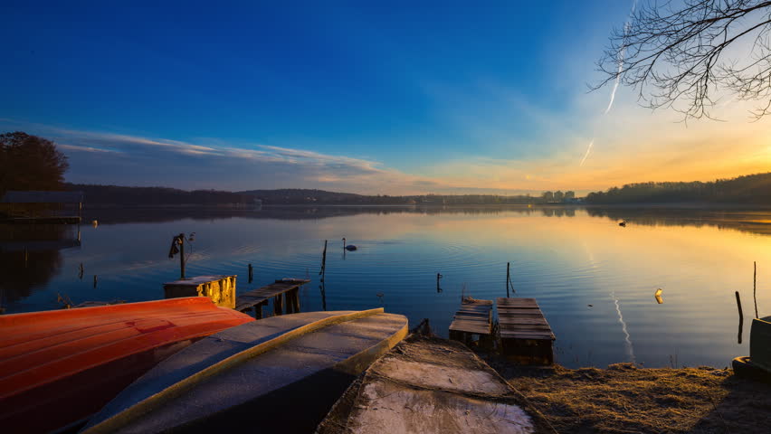 Sunrise over lake shore with fisherman