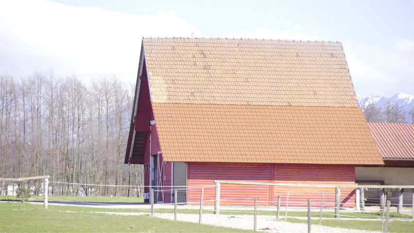 Big red stable building on ranch 4K. Static shot of countryside wooden farmhouse on a sunny day.