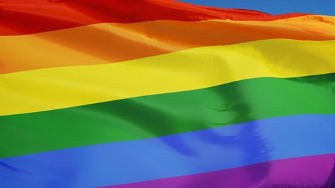 The gay pride rainbow flag waving in slow motion against clean blue sky, seamlessly looped, close up, isolated on alpha channel with black and white luminance matte, perfect for film, news