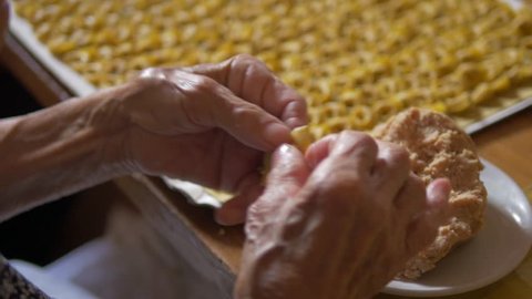 hands of an old woman preparing tortellini, a typical dish of the cuisine of Emilia. Hand made with fresh pasta, meat and Parmesan cheese.
