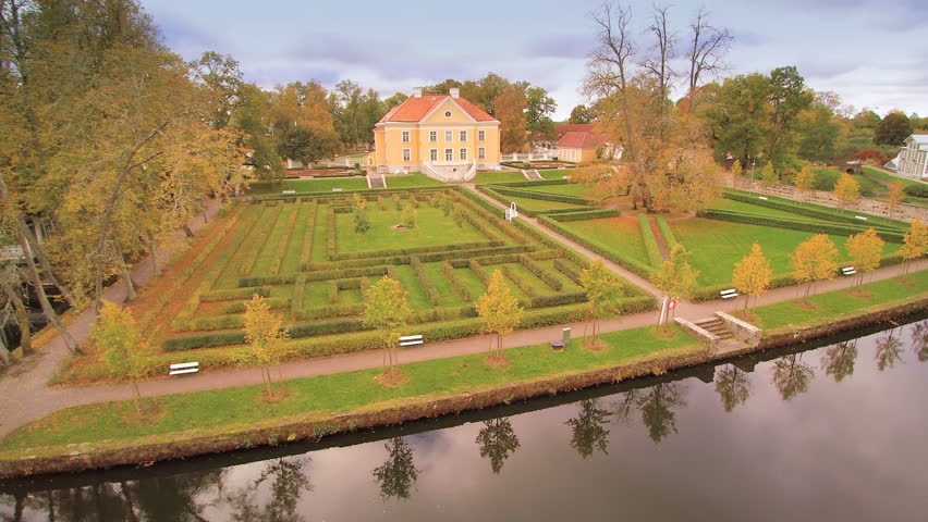 The lake fronting the Palmse manor with the grass landscape and the forest at the back