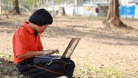 Student sitting and learning computer laptop on lawn in high school at LOEI Province, THAILAND.