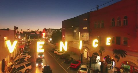LOS ANGELES - Circa 2015: Closeup aerial view of iconic Venice sign, revealing Venice Beach boardwalk and Pacific Ocean at sunset. 4K UHD.