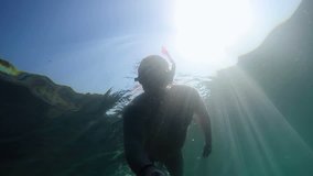 Man snorkeling in deep sea using waterproof action camera on selfie pole recording adventure underwater and taking selfie pictures