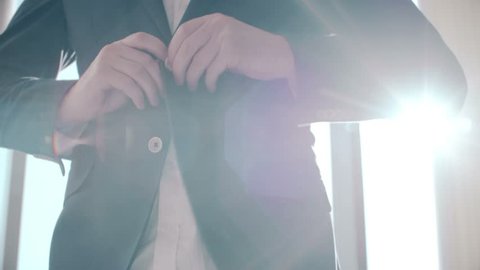 Buttoning a jacket. Stylish man in a suit fastening buttons on his jacket preparing to go out.