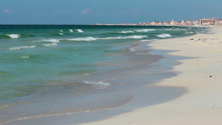 Alexandria, Egypt skyline shore behind waves smashing in from the Mediterranean Sea at el Agami beach on sunny day.  Looping video.