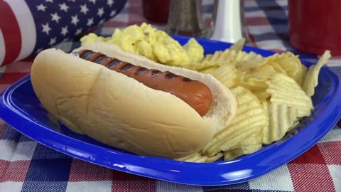 Squirting mustard onto a hot dog on a holiday picnic table - Βίντεο στοκ
