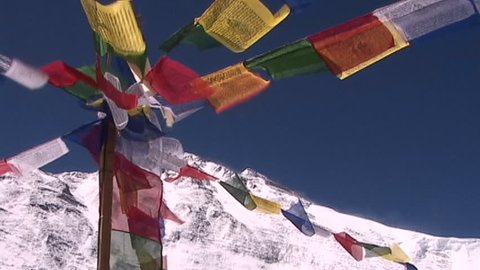 Buddhist prayer flags blowing in the wind as the summit of Mt. Everest looms in the background