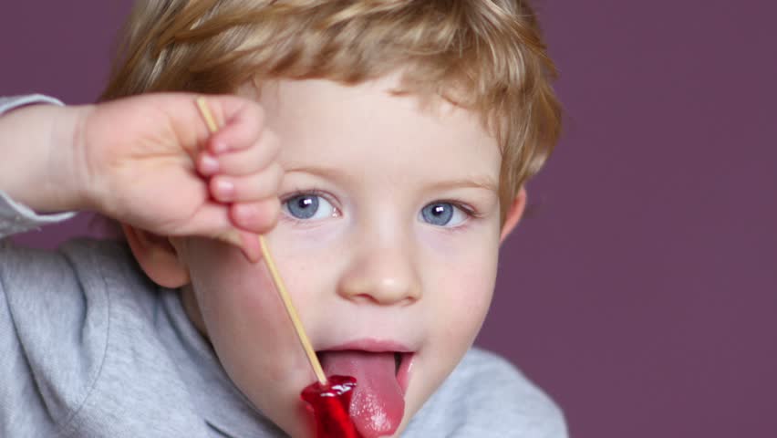 Boy enjoying red lollipop in chicken form