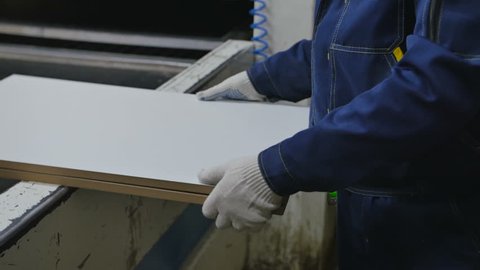 Worker puts a plywood on pressure machine table