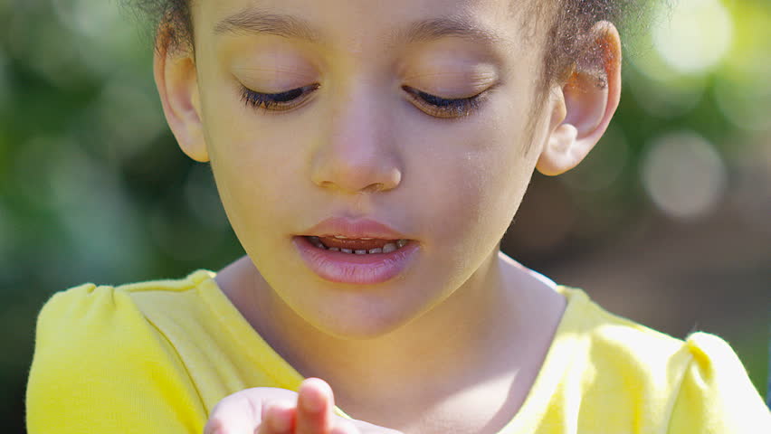 Close up of a young girl in wonder as she blows glitter from her hand, in slow motion 