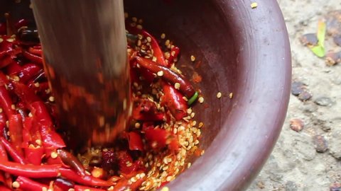 slow motion hit shot of red spicy chilli in mortal to cooking Thai food menu. Process to make Somtum Thai food from herb. 