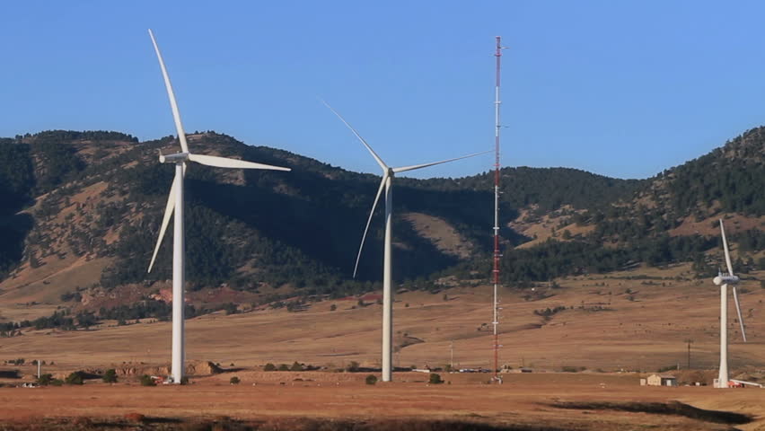 Large wind turbines generating alternative energy, with the Rocky Mountains in