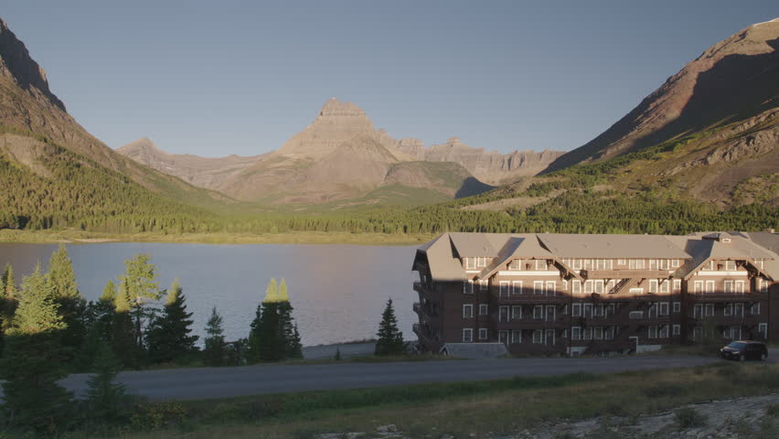 Car driving past hstoric Many Glaciers resort hotel inn in Glacier National Park, Montana.  4K.