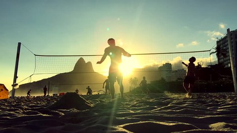 Silhouettes playing Brazilian beach futvolei (footvolley), a sport combining football (soccer) and volleyball, at sunset on Ipanema Beach, Rio