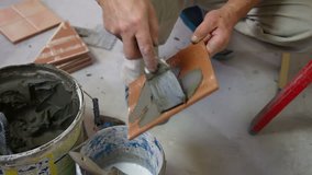 Man's hands show applying mortar to ceramic tile with a trowel, Close-up