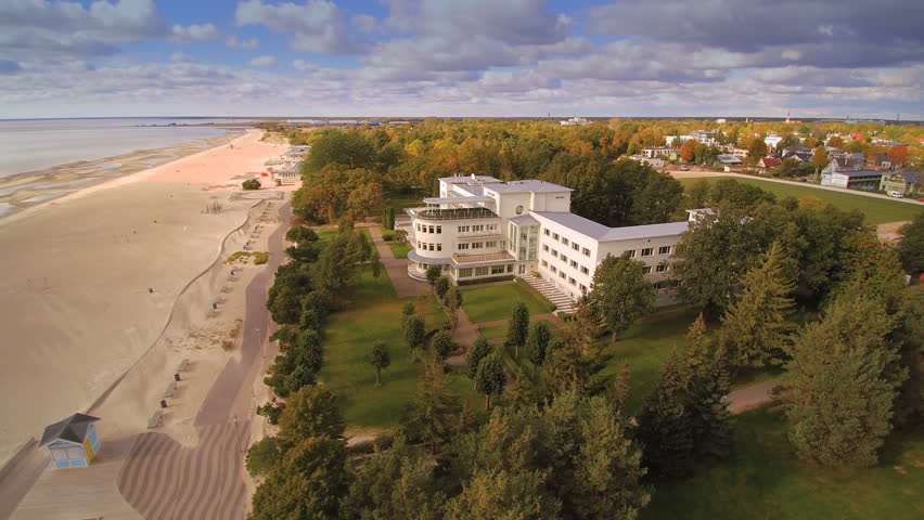 The big white building in front of the beach and the coastal white sand beach of Parnu in Estonia
