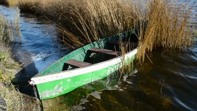 green boat in the autumn lake and waves