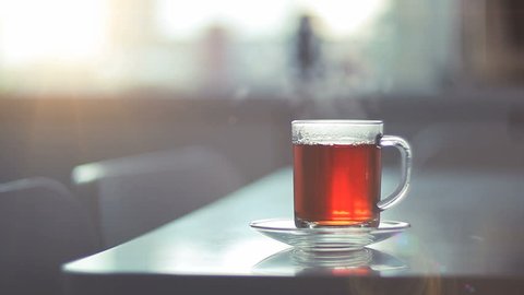 Seamless looped video with a glass of steaming hot tea on a table